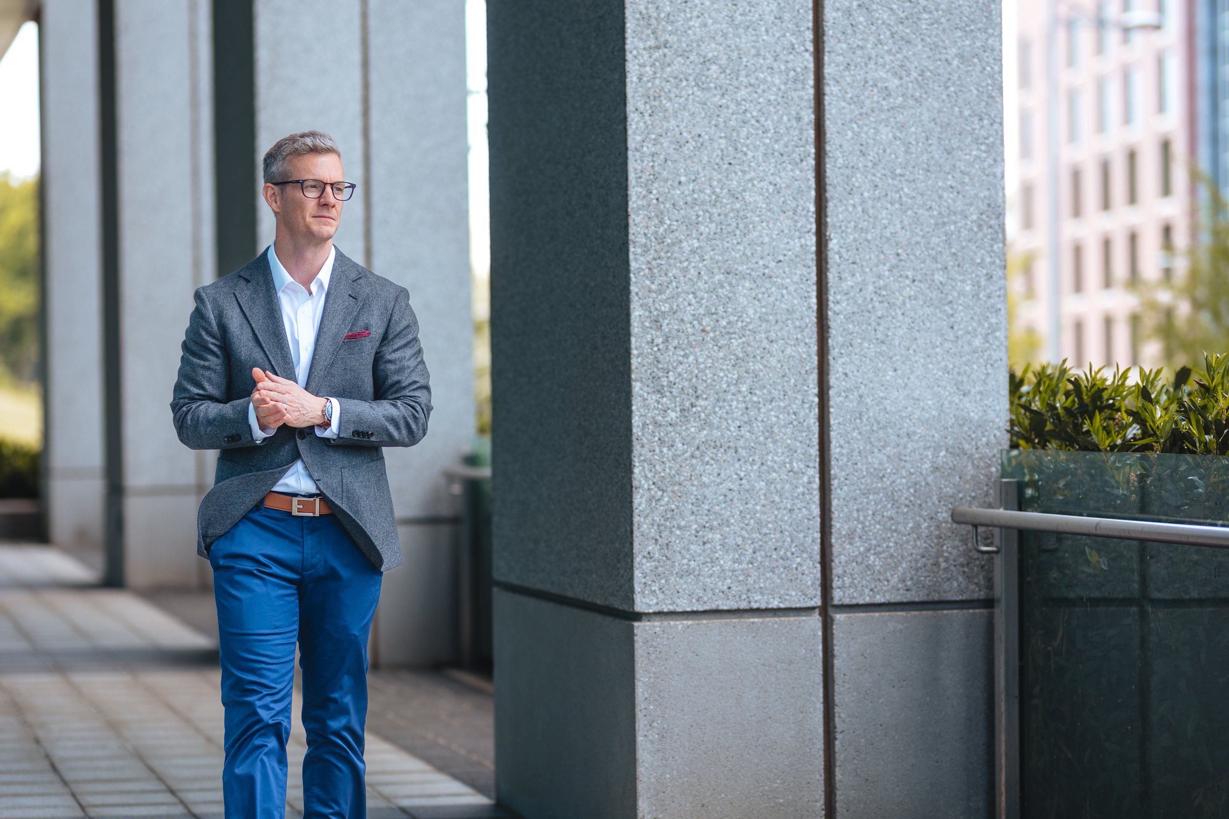 Eric McClerren walking along a granite colonnade, hands clasped, looking ahead
